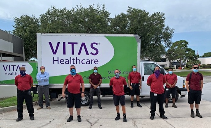 An HME team in protective masks stands next to a delivery truck