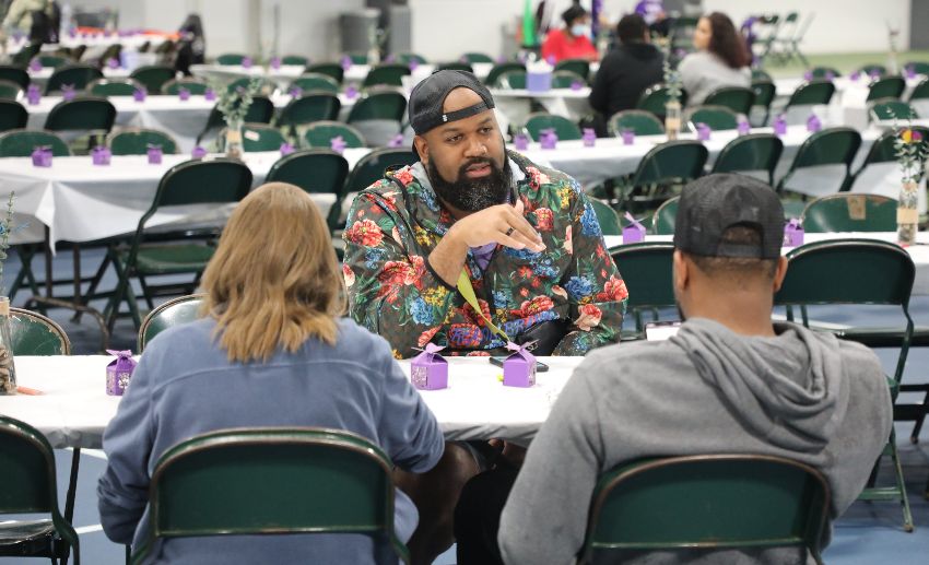 Three people talk at a table set up for guests