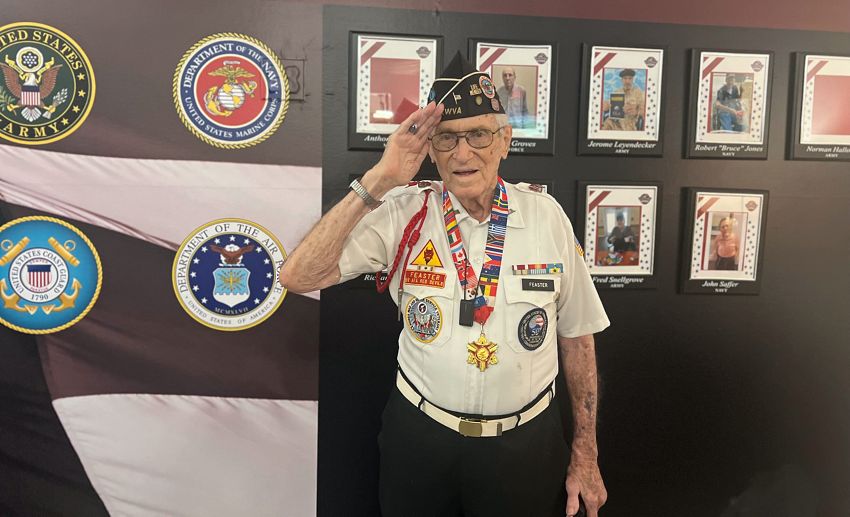 Jacob Feaster salutes in front of the veterans wall